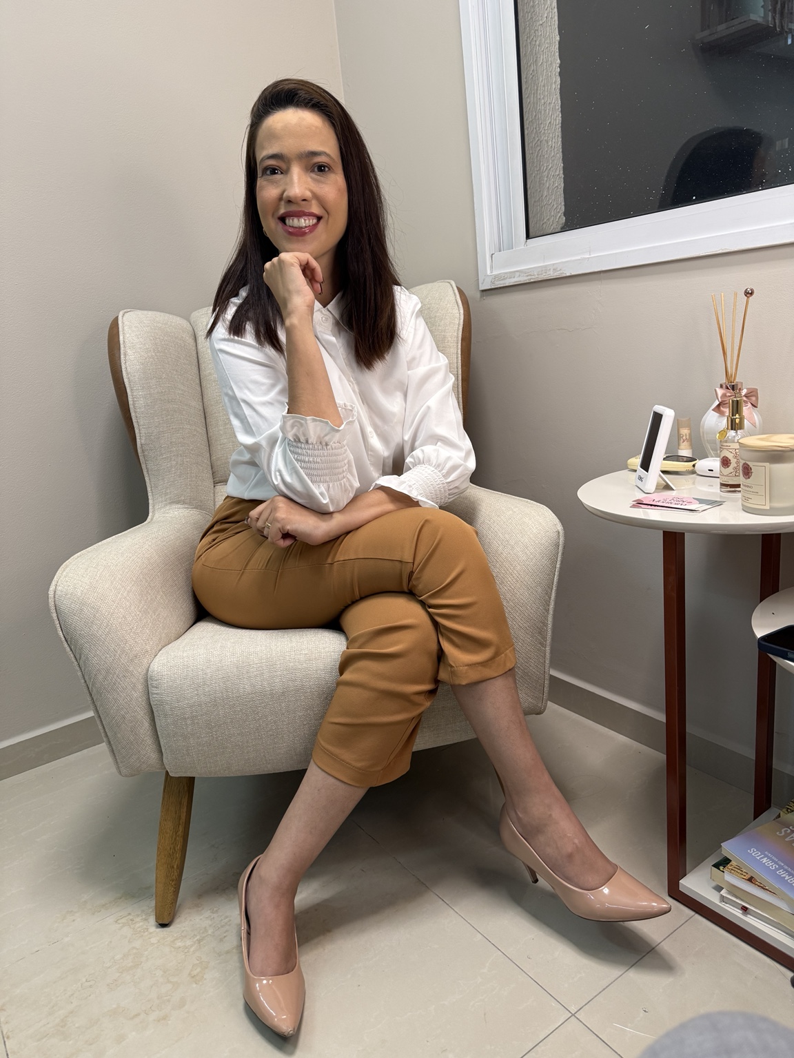 Fabiola Monteiro em seu consultório, em um ambiente acolhedor e iluminado por luz natural