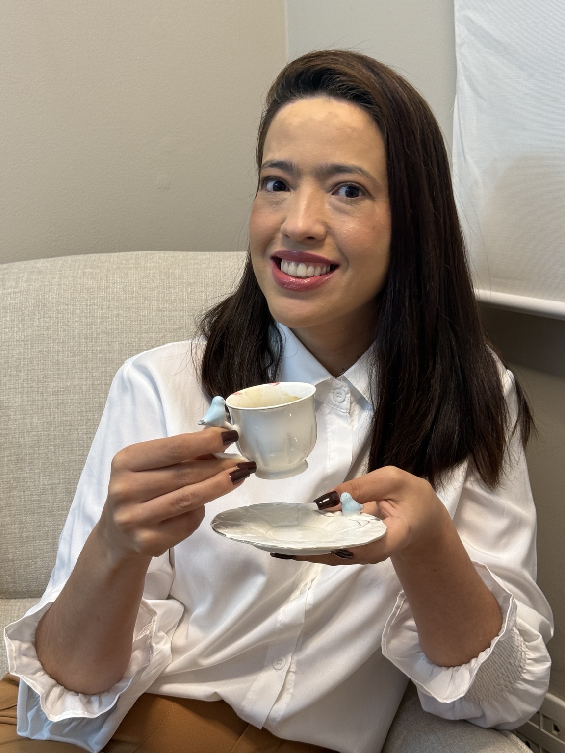 Fabiola Monteiro sorrindo com uma xícara de café em seu consultório